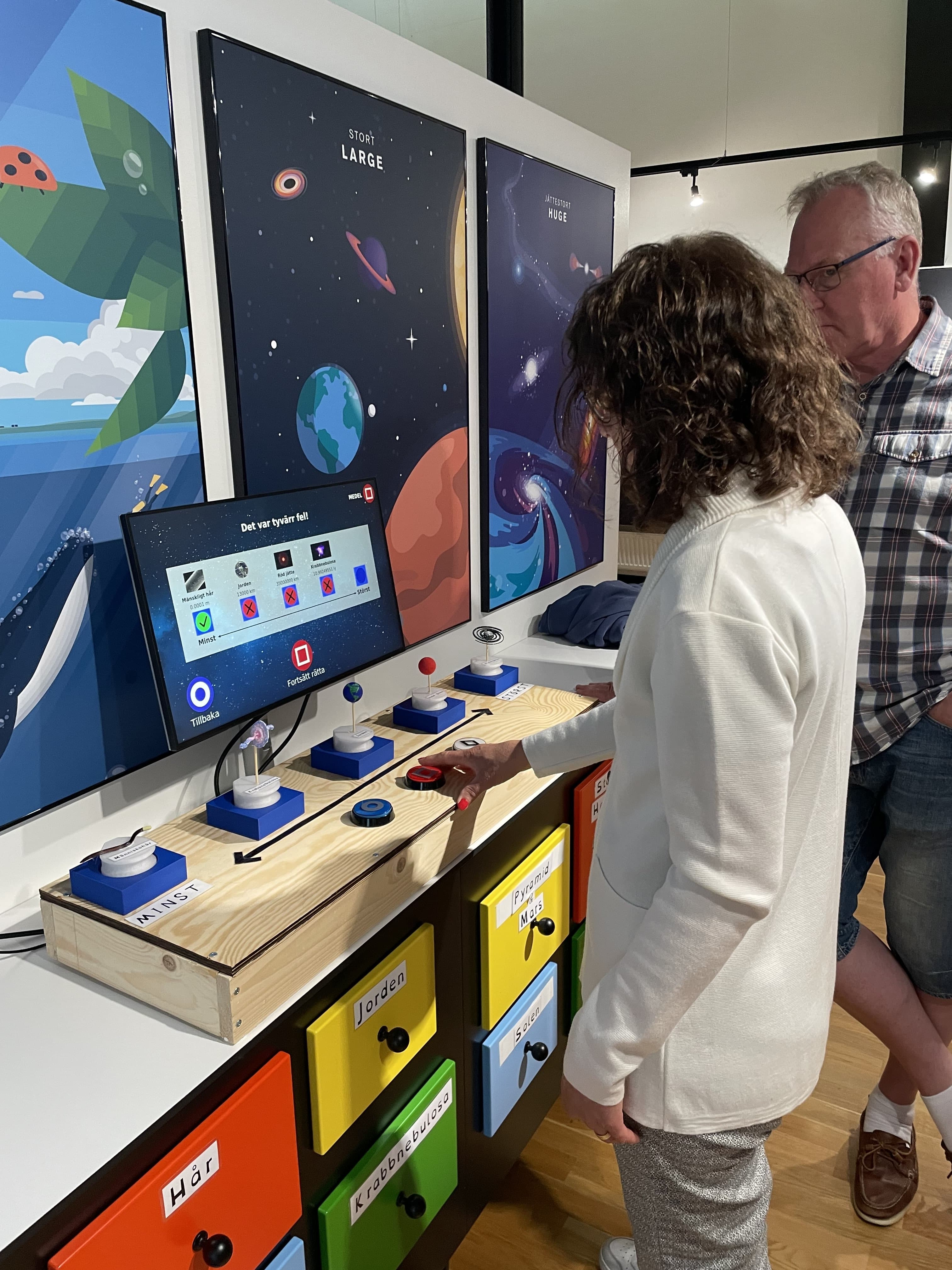 Visitors testing the installation, pressing buttons on the console while a question is shown on the screen.